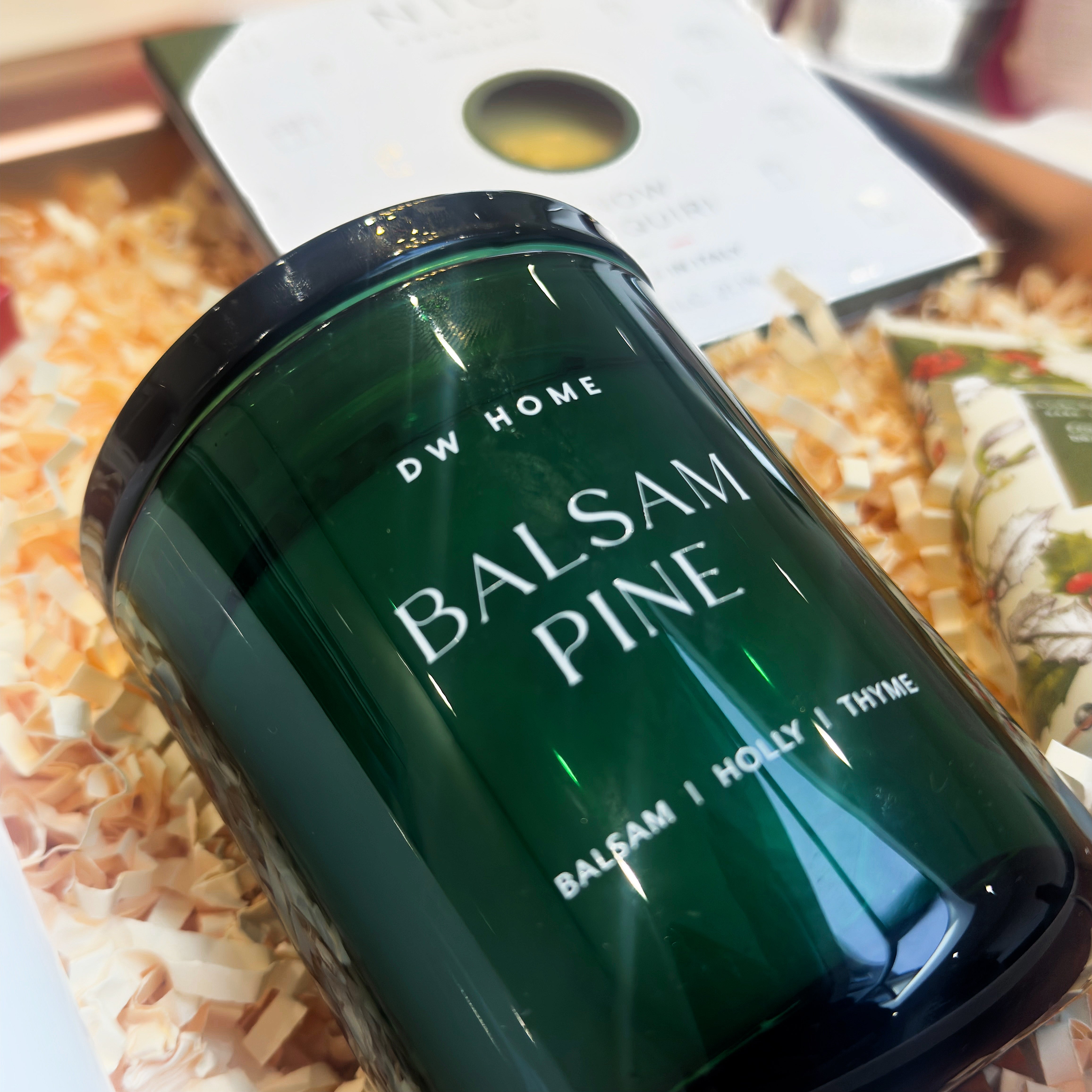 Green candle labeled 'Balsam Pine' by DW Home on a decorative surface.