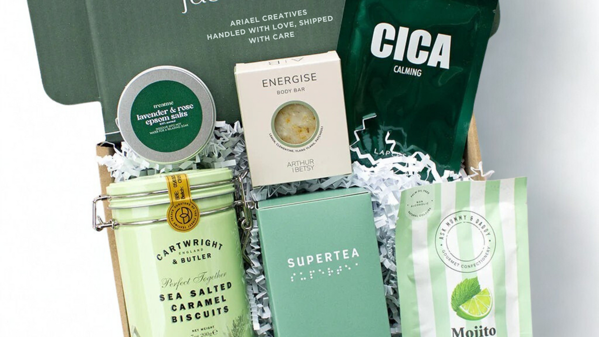 Gift set with various products including a book, tea, and cookies on a white background