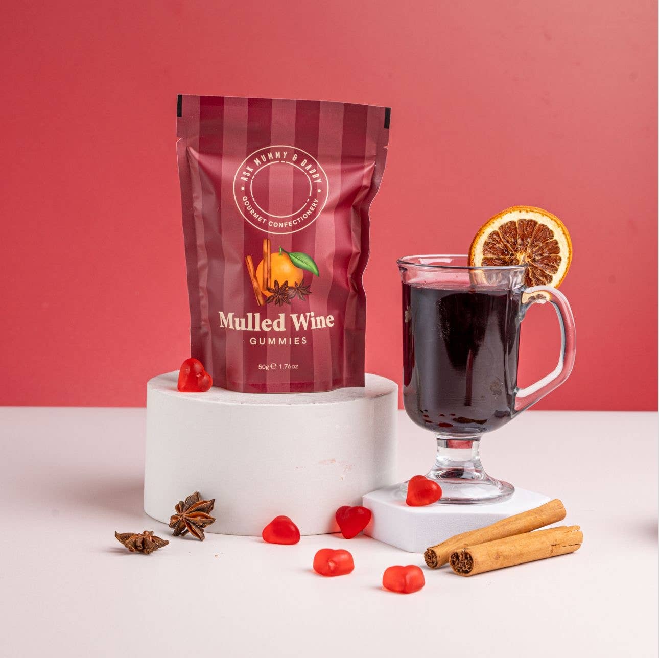 Mulled wine gummies package with a glass of mulled wine on a pink background