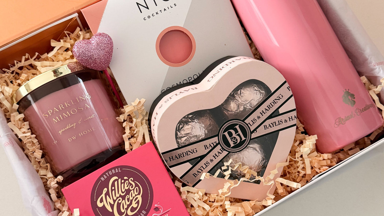 Gift set with pink tumbler, chocolate, and other items in a box